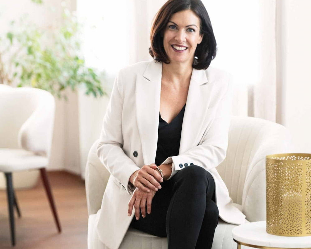 Katharina Schneider in weißen Blazer und hellem Hintergrund