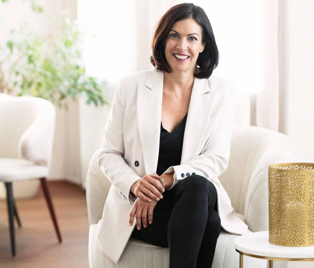 Katharina Schneider in weißen Blazer und hellem Hintergrund