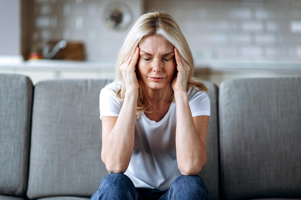 Frau mit Kopfschmerzen auf einer grauen Couch